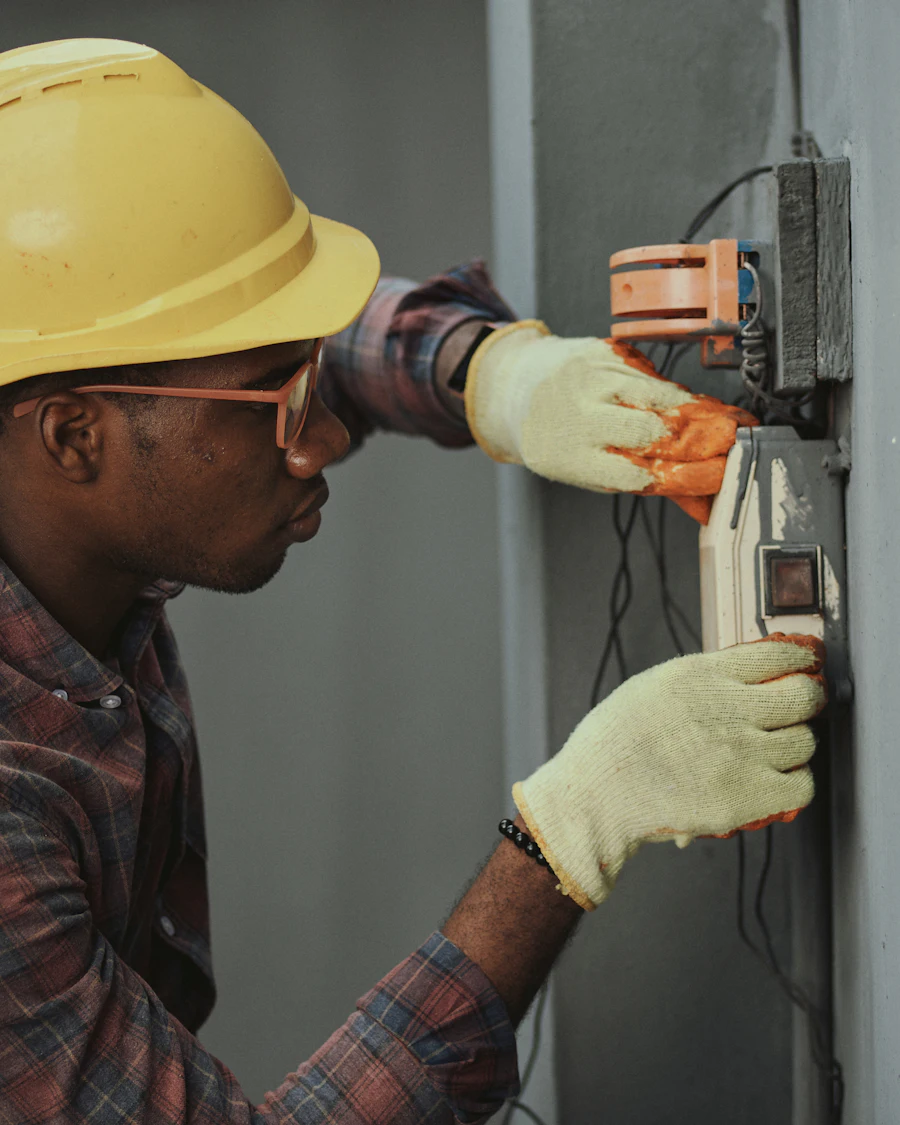 Electrician in a hard hat working on an electrical panel