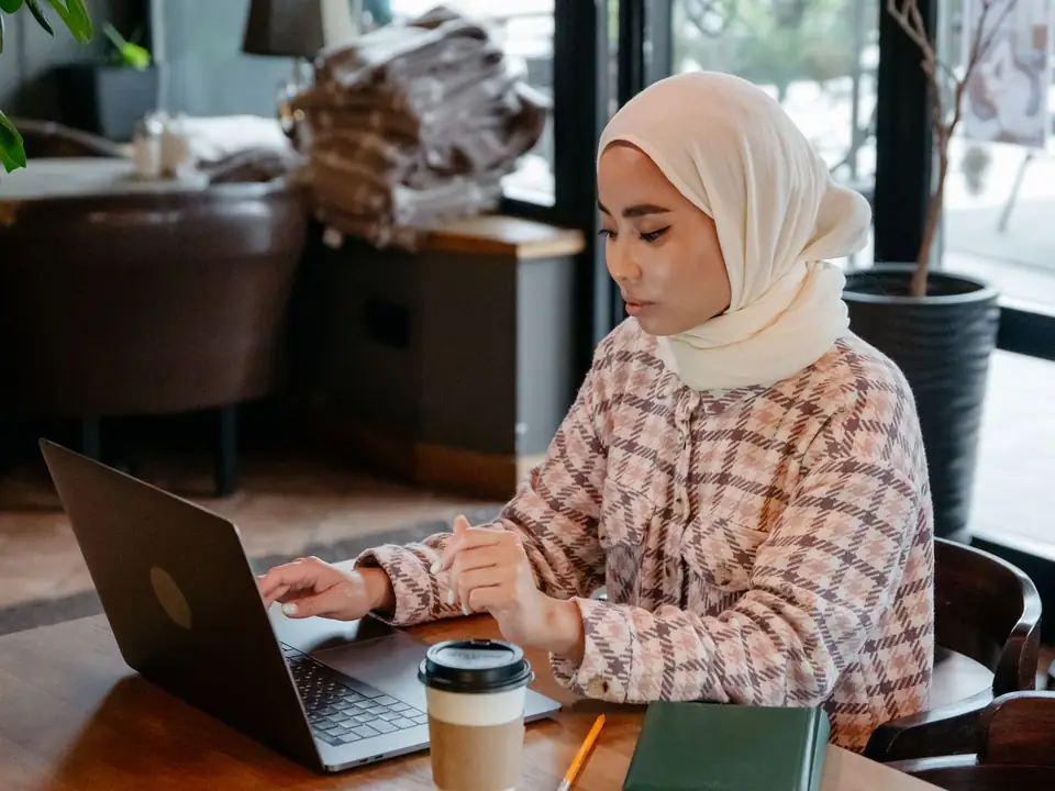 Freelancer in a hijab working on her laptop in a cafe