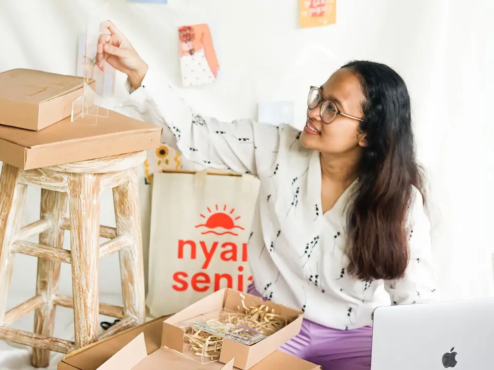 Online shop owner packing customer orders next to her laptop